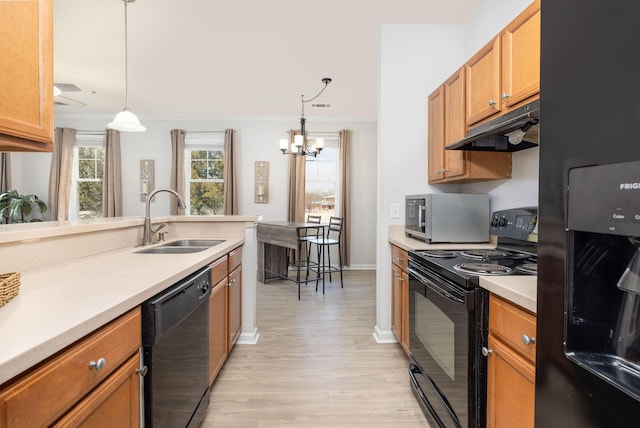 kitchen with under cabinet range hood, a sink, light countertops, black appliances, and pendant lighting