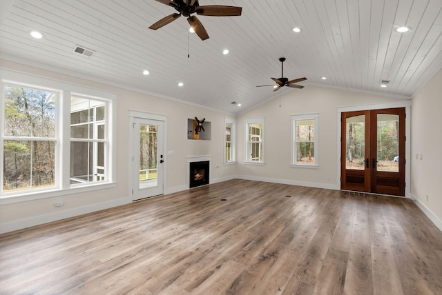 unfurnished living room featuring a warm lit fireplace, lofted ceiling, visible vents, light wood-style floors, and french doors