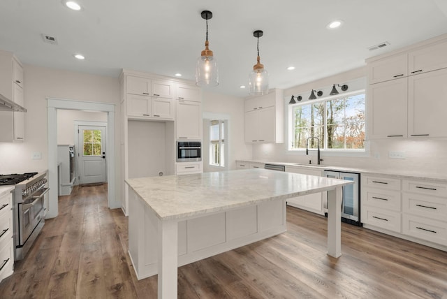 kitchen featuring light stone counters, wine cooler, stainless steel appliances, white cabinets, and a kitchen island