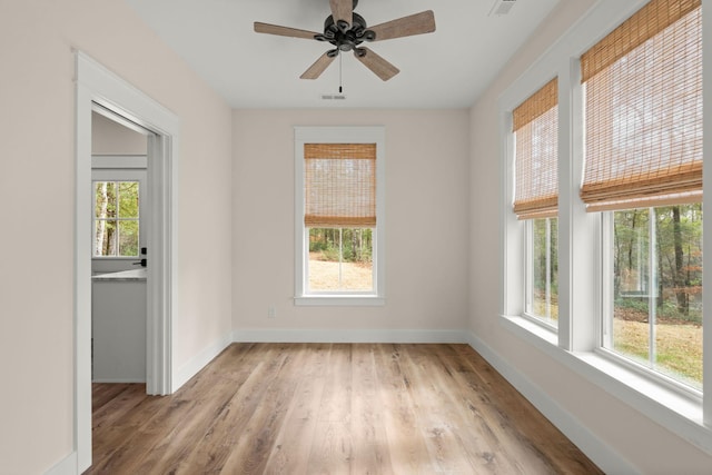 empty room with ceiling fan, light wood-type flooring, visible vents, and baseboards