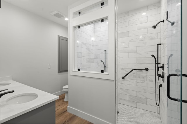 full bathroom with double vanity, baseboards, toilet, wood finished floors, and a sink