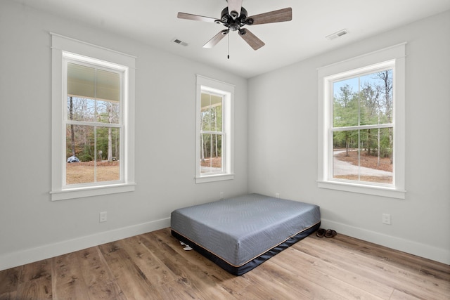bedroom featuring light wood-type flooring, multiple windows, and visible vents