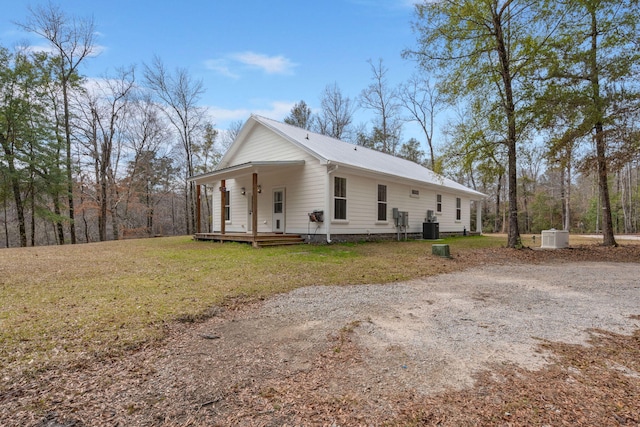 view of front of property with metal roof, a porch, cooling unit, driveway, and a front yard
