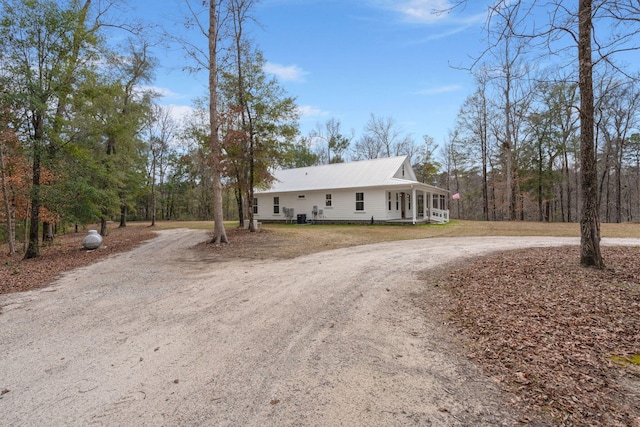 view of front of property featuring a sunroom, curved driveway, and metal roof