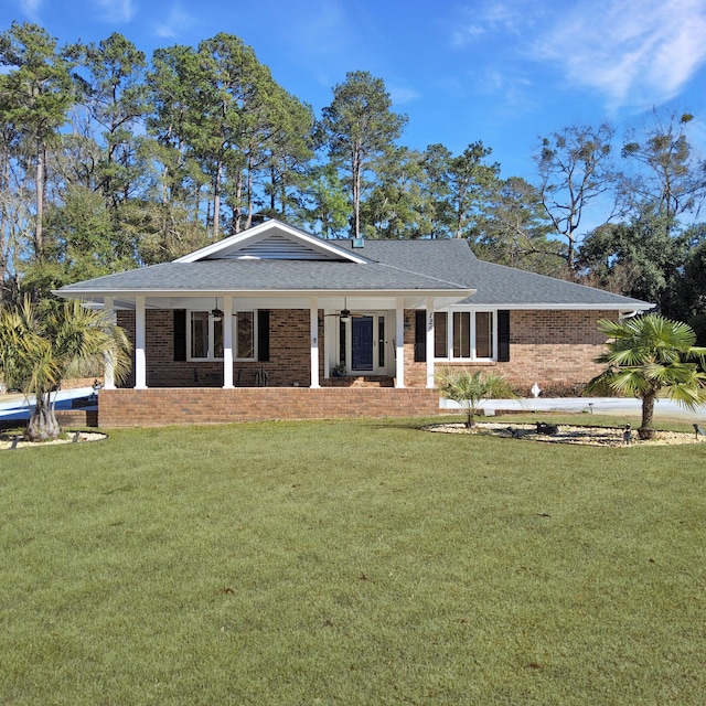 view of front of house featuring covered porch, roof with shingles, a front lawn, and brick siding