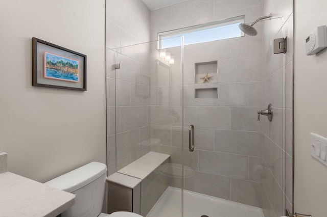 bathroom featuring a shower stall, toilet, and vanity