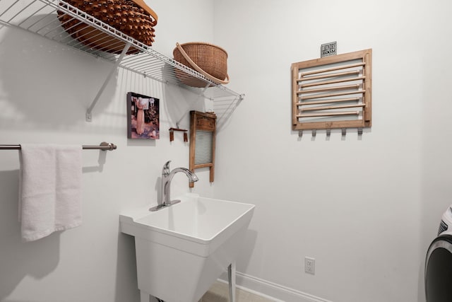 clothes washing area with a sink, washer / dryer, and baseboards