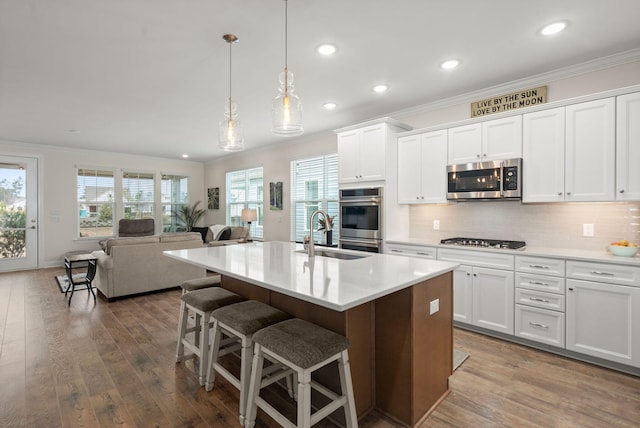 kitchen featuring stainless steel appliances, a sink, hardwood / wood-style flooring, and crown molding