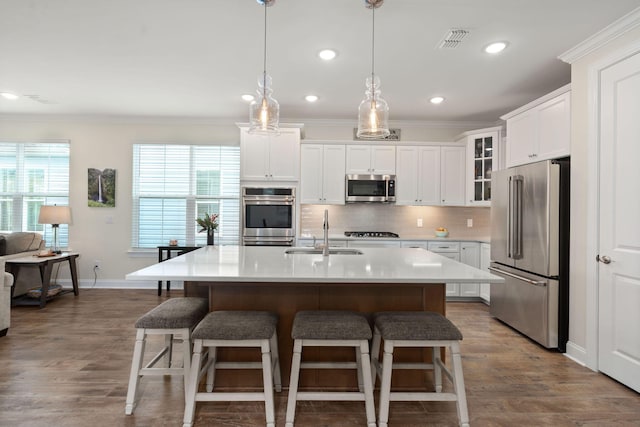 kitchen featuring appliances with stainless steel finishes, a sink, backsplash, and ornamental molding