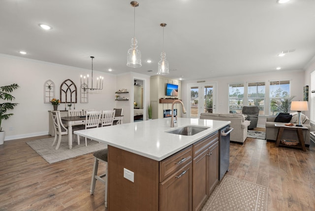 kitchen featuring light countertops, open floor plan, a sink, and wood finished floors