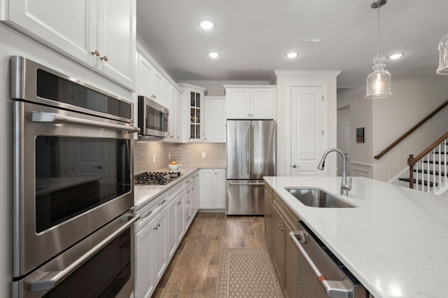 kitchen featuring wood finished floors, stainless steel appliances, ornamental molding, and a sink