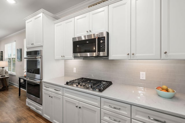 kitchen featuring stainless steel appliances, white cabinetry, decorative backsplash, dark wood-style floors, and crown molding