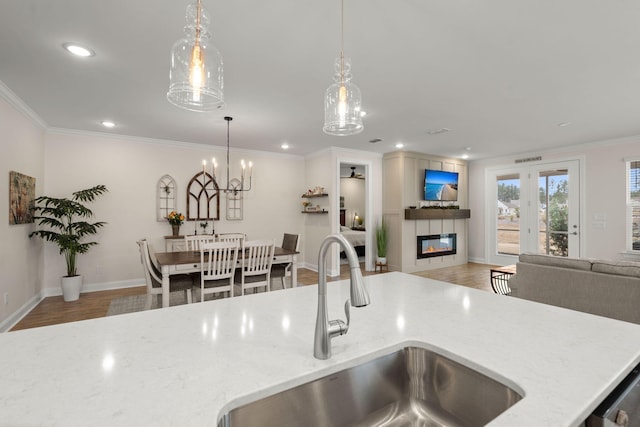 kitchen with open floor plan, a sink, light wood-style flooring, and crown molding