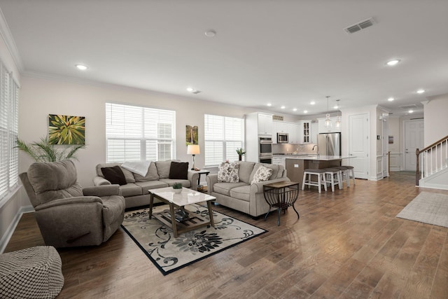 living area with recessed lighting, visible vents, stairs, ornamental molding, and dark wood-style floors