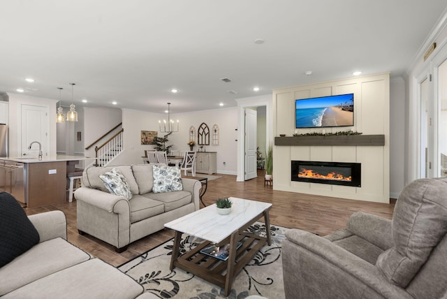 living room with light wood finished floors, crown molding, and a glass covered fireplace