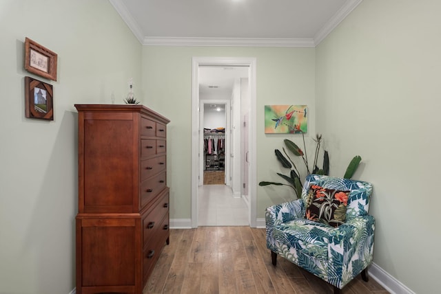 corridor featuring baseboards, light wood finished floors, and crown molding