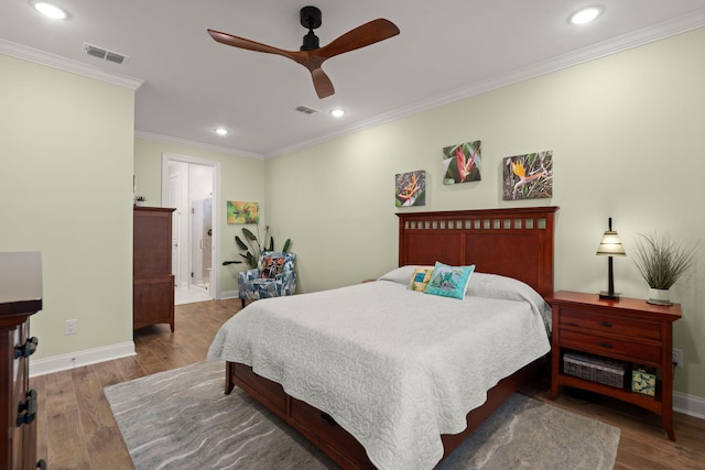 bedroom featuring visible vents, crown molding, baseboards, and wood finished floors