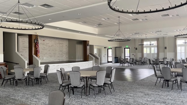 dining space featuring a high ceiling, visible vents, a raised ceiling, and wood finished floors