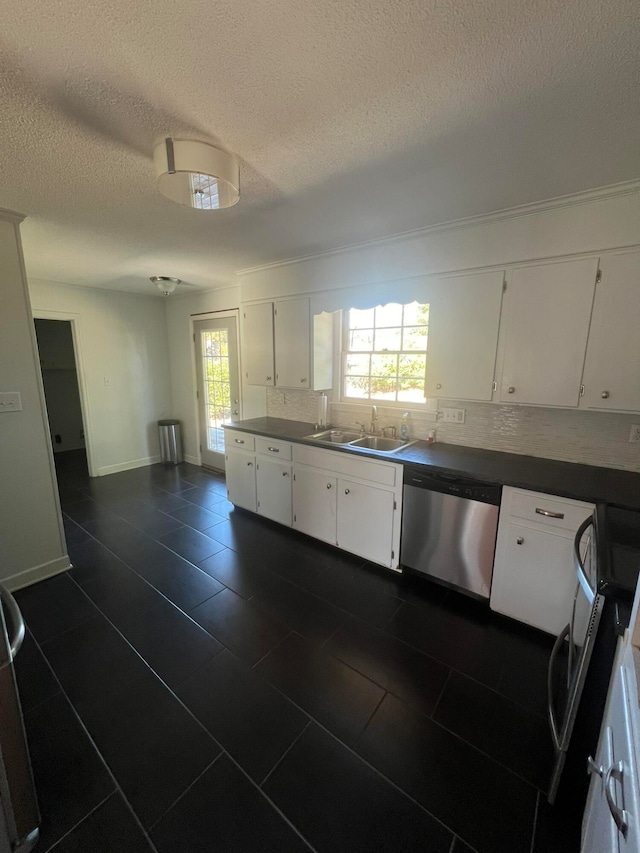 kitchen with sink, white cabinets, appliances with stainless steel finishes, a textured ceiling, and tasteful backsplash