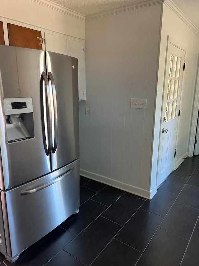 kitchen with a textured ceiling, stainless steel fridge with ice dispenser, dark tile patterned floors, and white cabinets