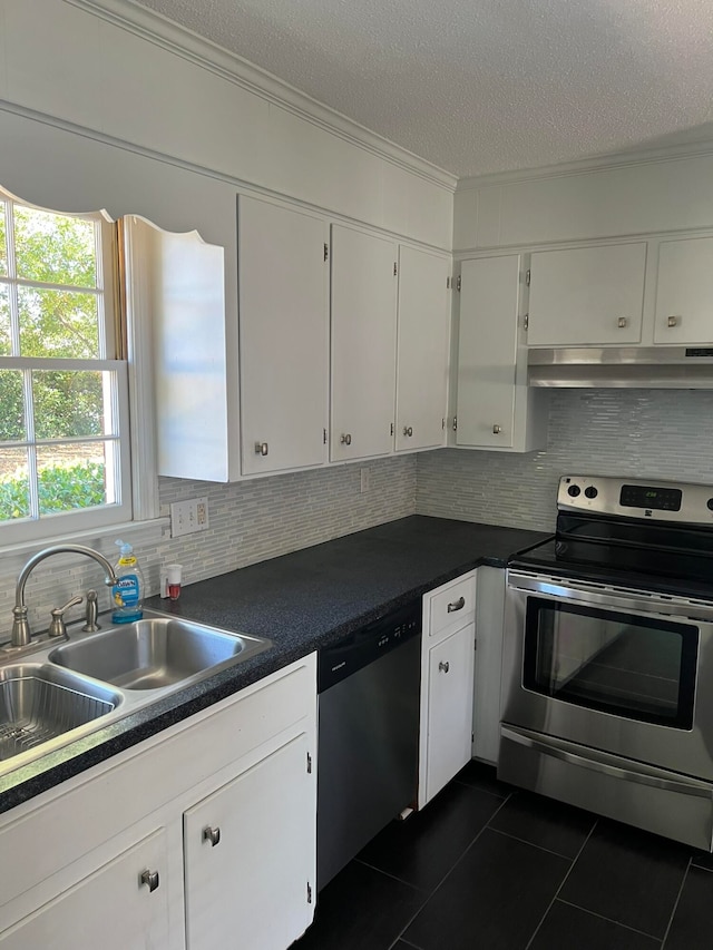 kitchen featuring decorative backsplash, white cabinets, dark tile patterned floors, sink, and stainless steel appliances