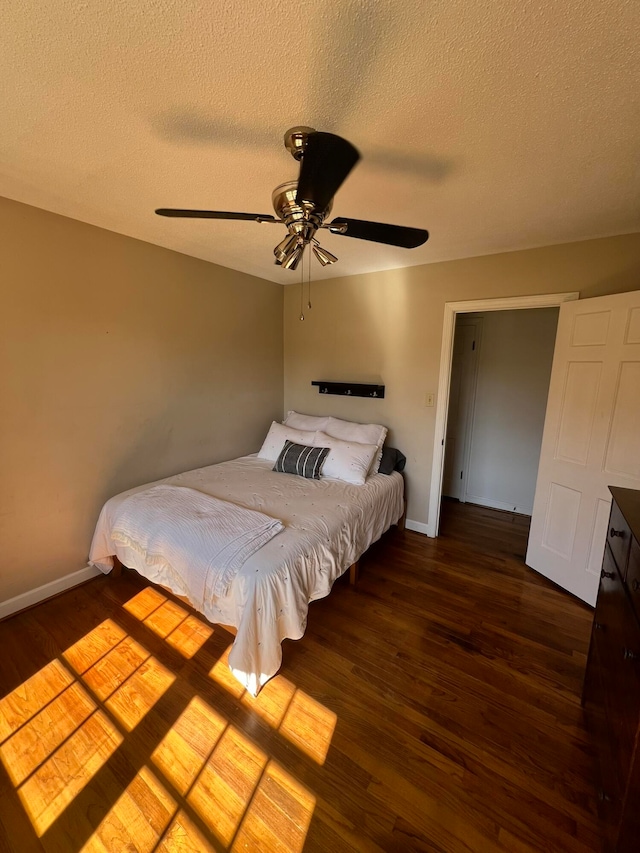 bedroom with ceiling fan, a textured ceiling, and dark hardwood / wood-style flooring