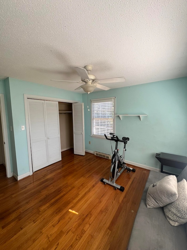 workout area with hardwood / wood-style floors, a textured ceiling, and ceiling fan