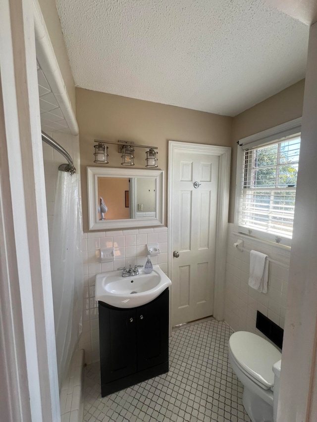 bathroom featuring tile walls, toilet, vanity, curtained shower, and tile patterned floors