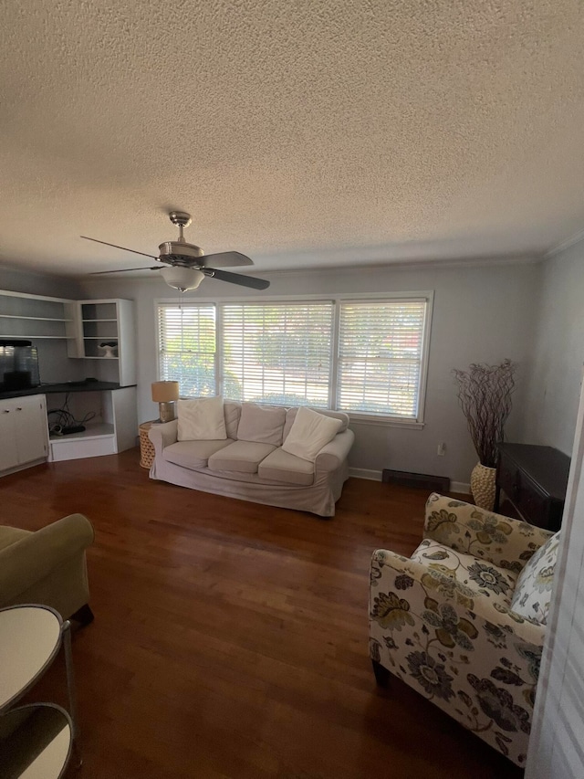 living room with a wealth of natural light, a textured ceiling, dark hardwood / wood-style floors, and ceiling fan