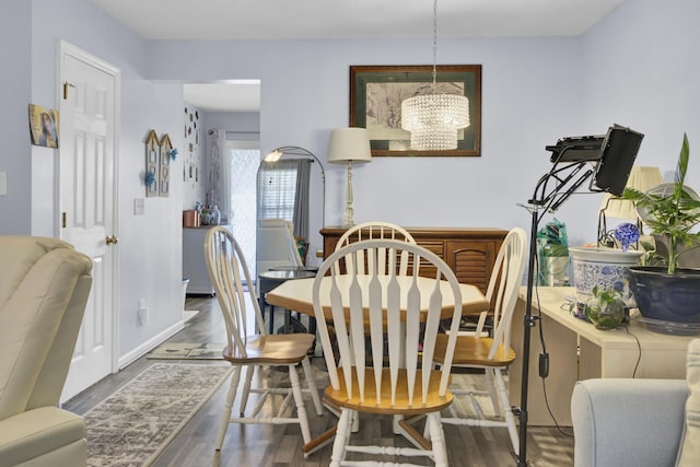 dining space with baseboards, an inviting chandelier, and wood finished floors