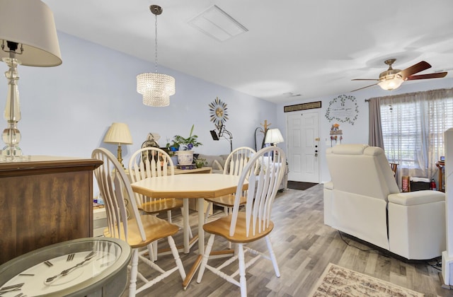 dining room with ceiling fan with notable chandelier and wood finished floors