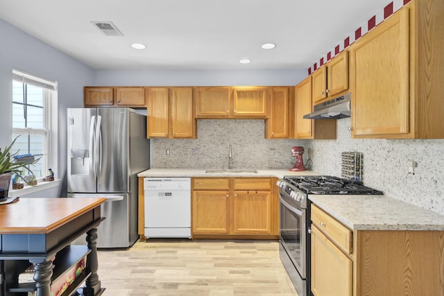 kitchen featuring tasteful backsplash, visible vents, under cabinet range hood, appliances with stainless steel finishes, and a sink