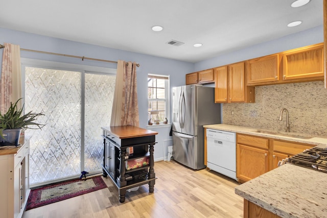 kitchen featuring visible vents, stainless steel refrigerator with ice dispenser, a sink, light wood finished floors, and dishwasher