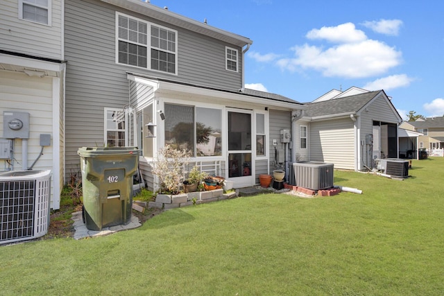 rear view of property with a lawn, central AC, and a sunroom