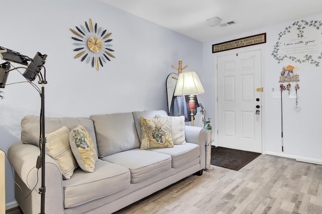 living room featuring baseboards, visible vents, and light wood finished floors