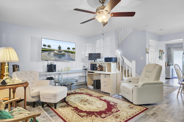 living room featuring light wood finished floors, stairway, and a ceiling fan