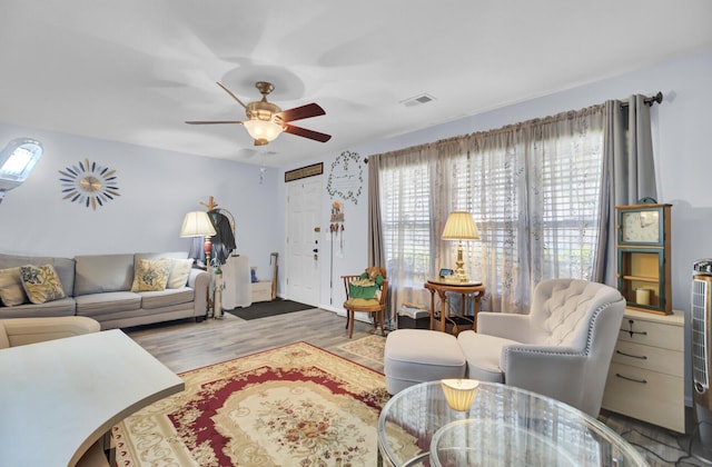 living area featuring wood finished floors, visible vents, and ceiling fan