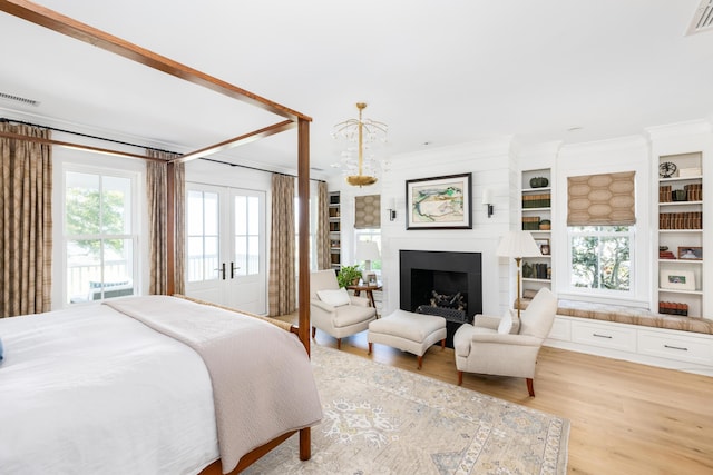 202 Bank St, Mount Pleasant, SC 29464 - bedroom with light wood finished floors, french doors, crown molding, and a fireplace