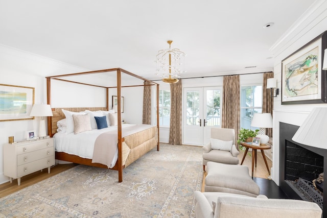 202 Bank St, Mount Pleasant, SC 29464 - bedroom featuring ornamental molding, a fireplace, wood finished floors, a chandelier, and french doors