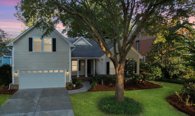 front of property featuring a lawn, covered porch, and a garage