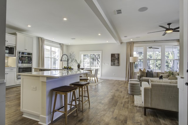 kitchen featuring sink, white cabinets, a center island with sink, and a breakfast bar