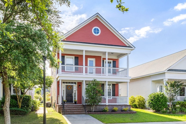 view of front of house with covered porch, a front yard, central AC, and a balcony