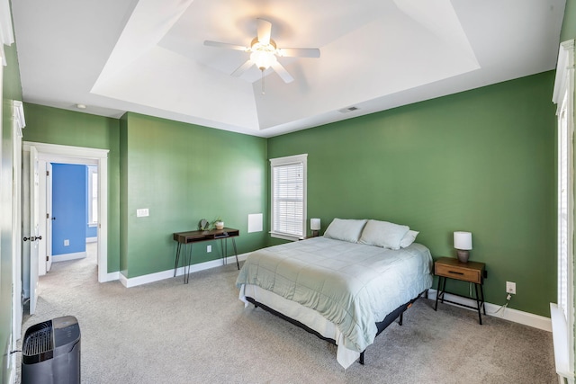 bedroom with baseboards, ceiling fan, carpet, and a tray ceiling