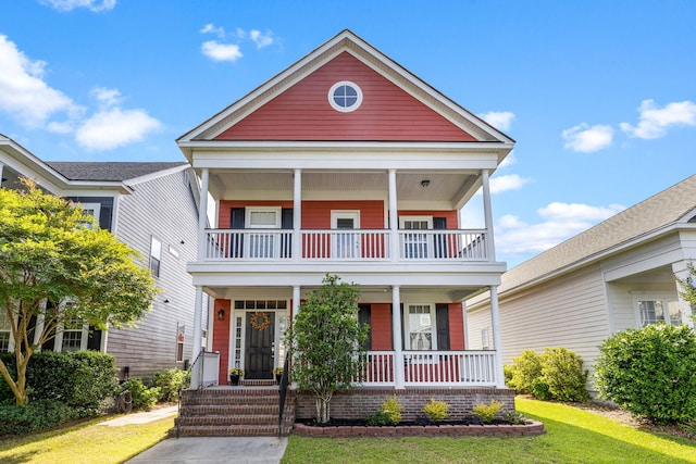 view of front of home with a porch, a balcony, and a front lawn