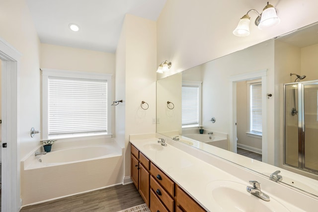 bathroom featuring a stall shower, a sink, a bath, and wood finished floors