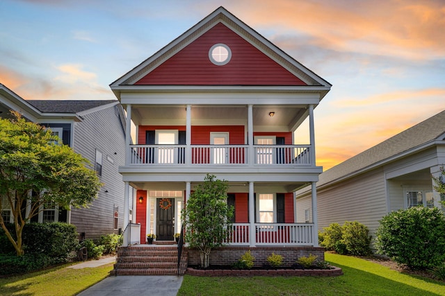 view of front facade featuring a porch, a balcony, and a front yard