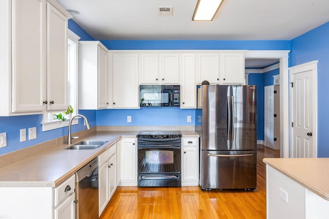 kitchen featuring a sink, light wood-style flooring, black appliances, and light countertops
