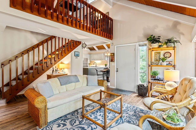 living room with beamed ceiling, high vaulted ceiling, hardwood / wood-style floors, sink, and an inviting chandelier