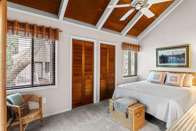 carpeted bedroom with ceiling fan, vaulted ceiling with beams, wood ceiling, and multiple closets