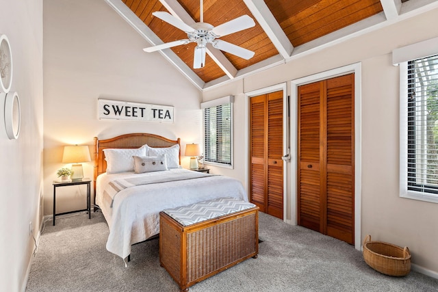 carpeted bedroom featuring ceiling fan, two closets, beamed ceiling, and wood ceiling